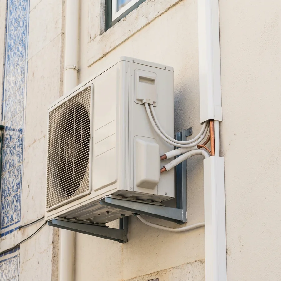 Outdoor air-conditioner condenser neatly bracket-mounted on a Lisbon façade with tidy pipe trunking